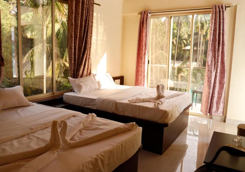 a hotel room with two beds and a window at Royal Breeze Resort in Alibag