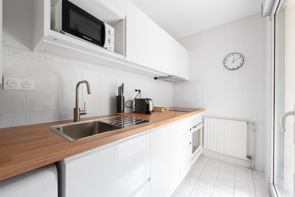 une cuisine blanche avec un évier et un micro-ondes dans l'établissement T2 Centre Ville avec Parking Gratuit et Jardin, à Toulouse