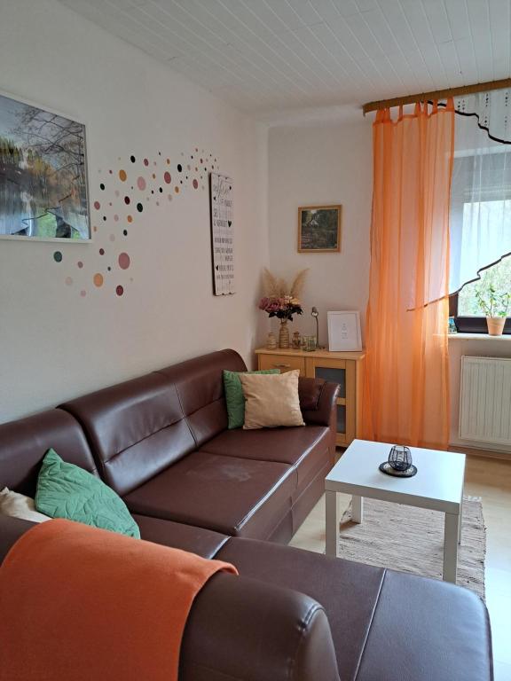 ein Wohnzimmer mit einem braunen Sofa und einem Tisch in der Unterkunft Ferienwohnung Niklas in Völklingen
