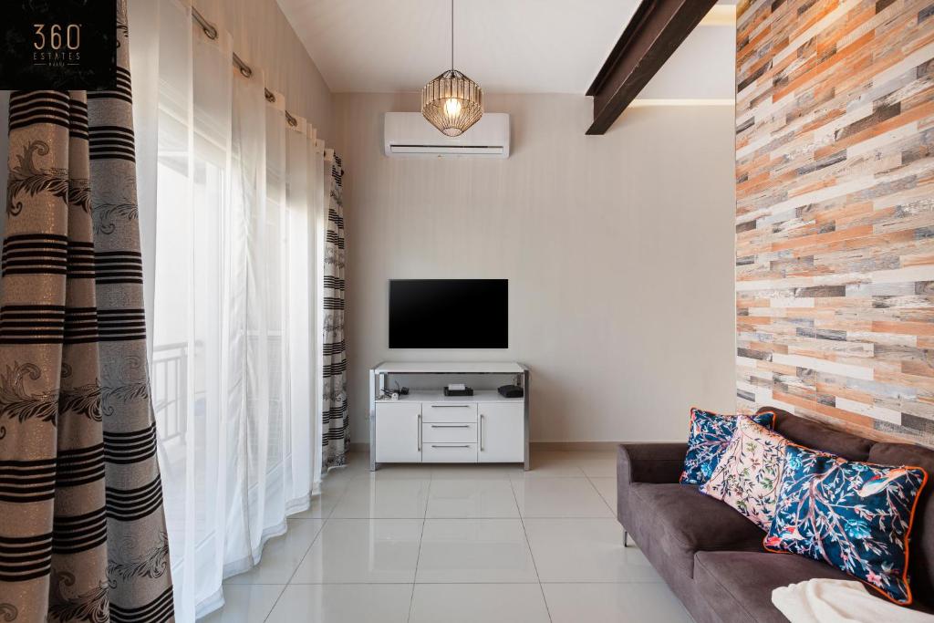 a living room with a couch and a flat screen tv at Lovely 2BR home in St Julians with Private Balcony by 360 Estates in St. Julianʼs