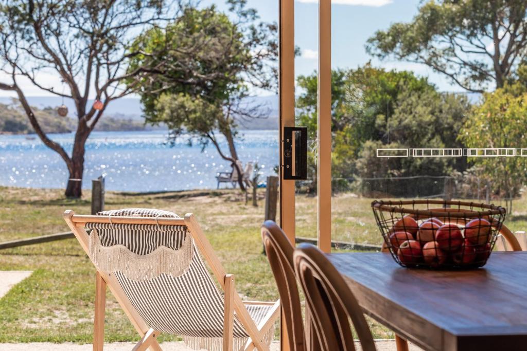 una mesa con sillas y una cesta de fruta. en Lobster Pot Cabin, en Coles Bay