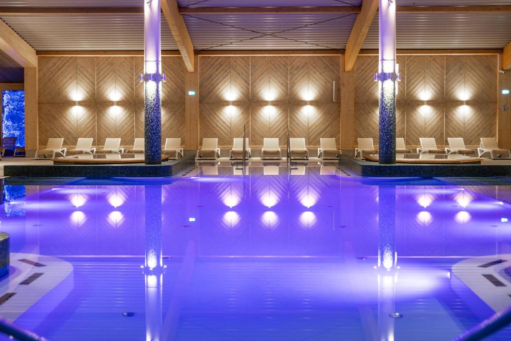 a swimming pool with chairs in a hotel at Aries Hotel & SPA Szczyrk in Szczyrk