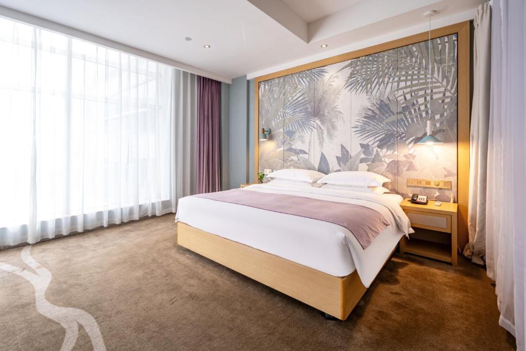 a bedroom with a large bed with a large painting on the wall at Xiamen Shuyue Hotel in Xiamen