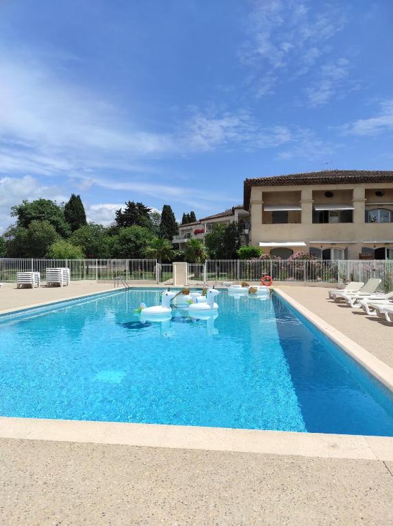 une grande piscine d'eau bleue en face d'un bâtiment dans l'établissement Studio 314 - LES SUITES DE ROBINSON - Résidence avec piscine en bord de Siagne, à Mandelieu-La-Napoule, à Mandelieu-la-Napoule