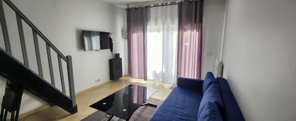 ein Wohnzimmer mit einem blauen Sofa und einem Fenster in der Unterkunft Duplex dans pavillon neuilly sur marne entre Paris et disney in Neuilly-sur-Marne