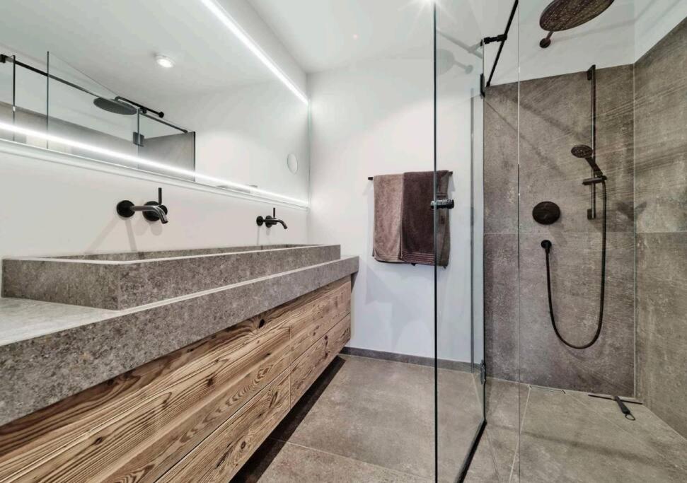 uma casa de banho com uma cabina de duche em vidro e um lavatório. em Spa, Sport & City Luxury Ski-in Ski-Out Apartment em Kitzbühel