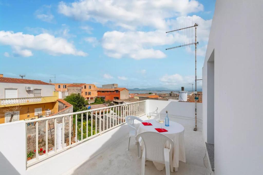 einen weißen Balkon mit einem weißen Tisch und Stühlen in der Unterkunft Domo de Maria - Calamenhir in SantʼAntìoco