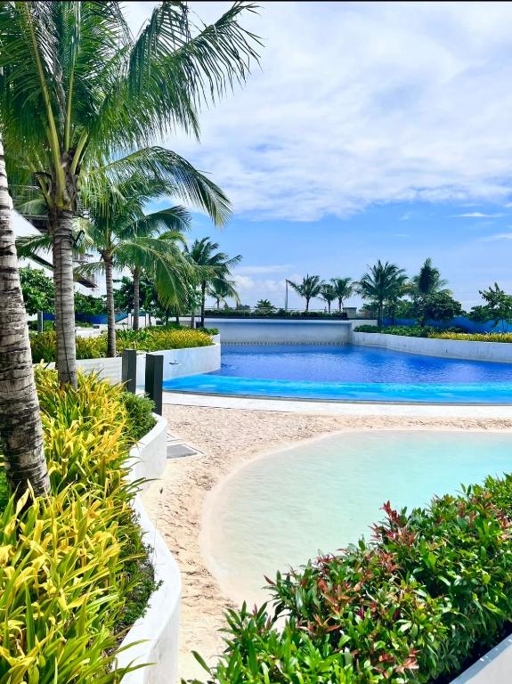 a swimming pool with palm trees and a beach at Condo At Azure North San Fernado in San Fernando