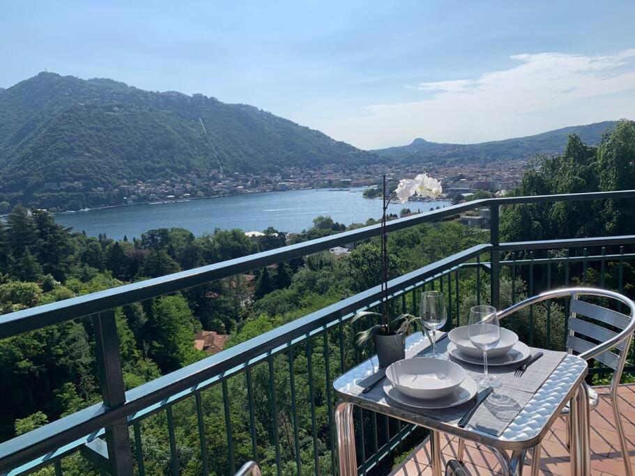 a table with plates and wine glasses on a balcony at La finestra sul lago di Como in Como