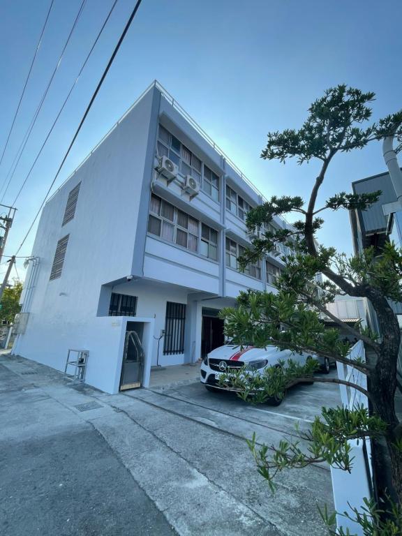 a white building with a car parked in front of it at 新化61行館民宿 