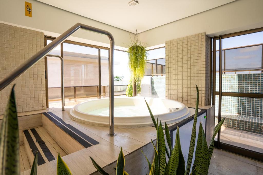 une grande salle de bains avec bain à remous et plantes dans l'établissement Hotel Cabo Branco Atlântico, à João Pessoa