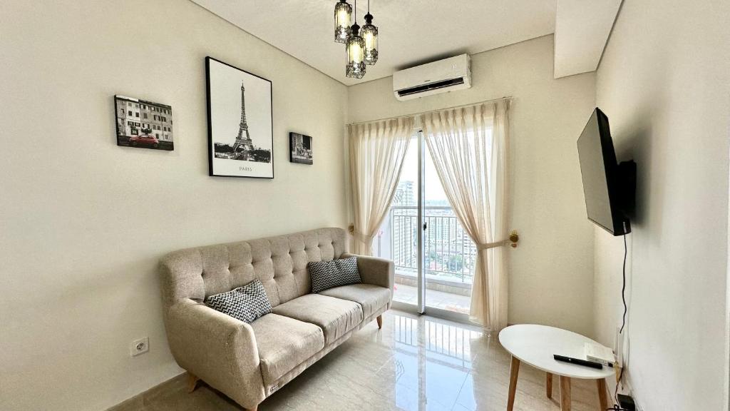 uma sala de estar com um sofá e uma televisão em Apartemen Podomoro View Kota 2BR lantai 17 Full perabot em Medan