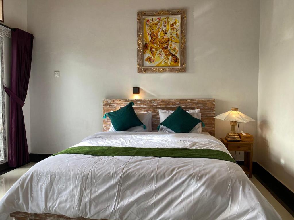 1 dormitorio con 1 cama blanca grande con almohadas verdes en Umah Saren Homestay, en Undisan