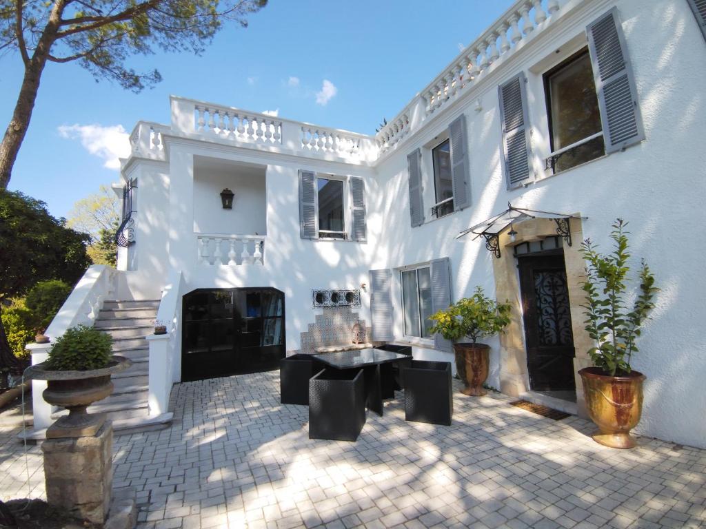 une maison blanche avec une cour et une terrasse dans l'établissement Le Clos Fontaine, à Grasse