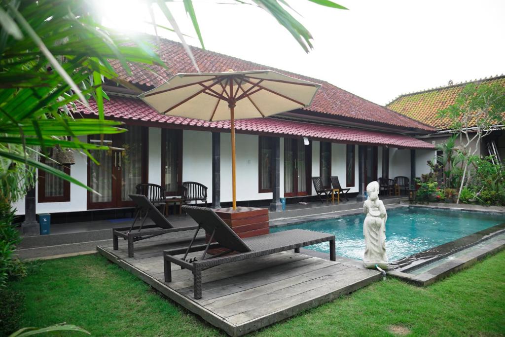 - une piscine avec 2 chaises et un parasol à côté d'une maison dans l'établissement Kim Homestay, à Ubud