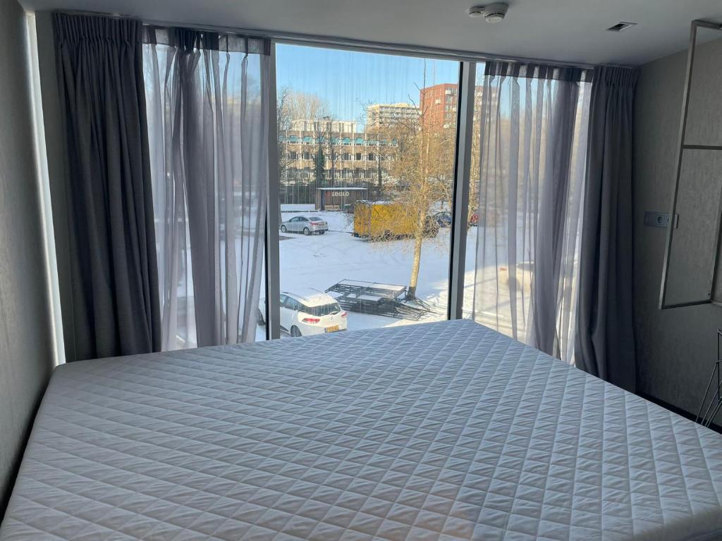 - une chambre avec un lit et une grande fenêtre dans l'établissement Diamond Capsule Hotel Amsterdam South, à Amstelveen