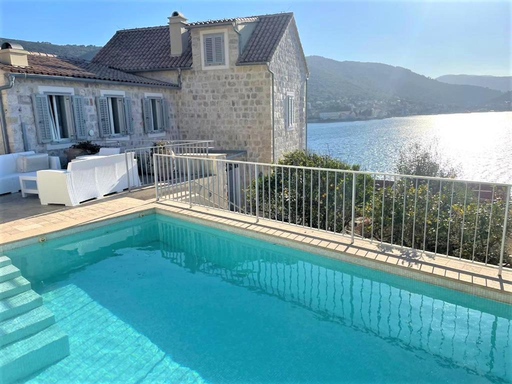 una piscina di fronte a una casa vicino all'acqua di JASMINE VILLA luxury house with private pool, spacious terraces and spectacular sea views a Vis