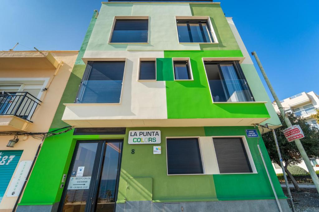 un bâtiment vert avec un panneau devant lui dans l'établissement La Punta COLORS By DLV, à La Vila Joiosa