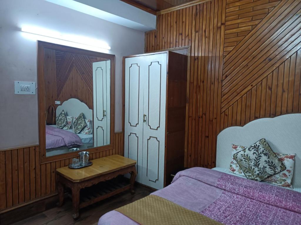 a bedroom with two beds and a table and a mirror at zoz sm 5 in Shimla