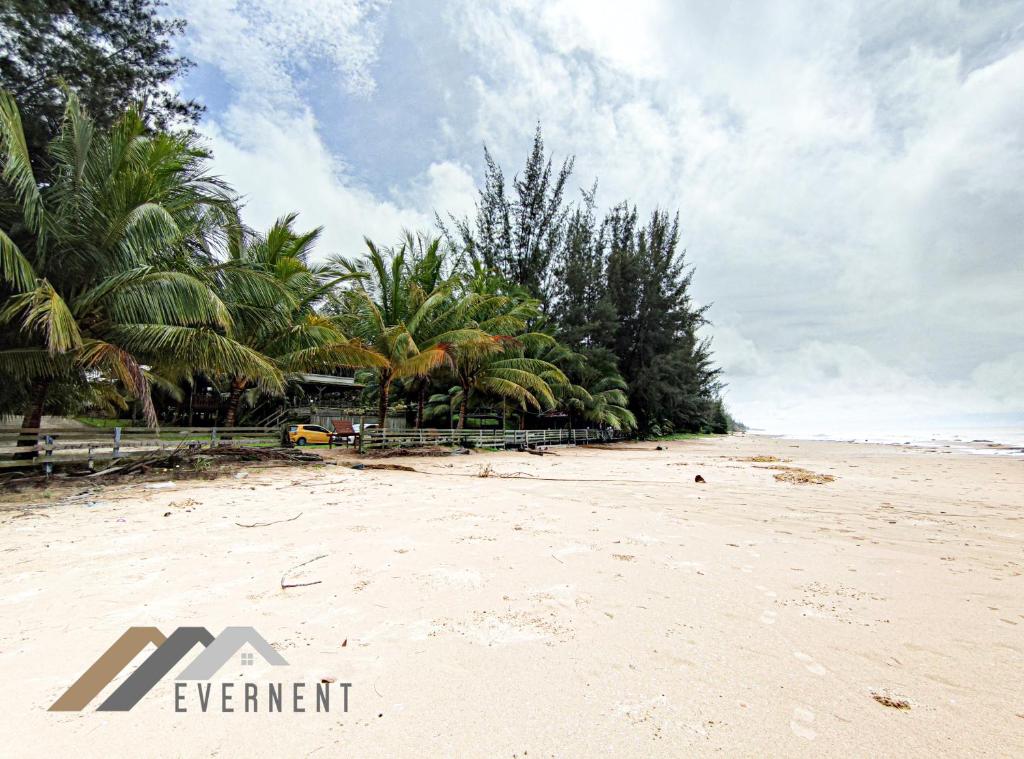 a sandy beach with palm trees on the horizon at Tim Seaside Resort by Evernent in Miri