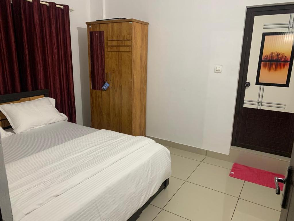 um quarto com uma cama e um armário de madeira em Wayanad Rooms Izza em Sultan Bathery