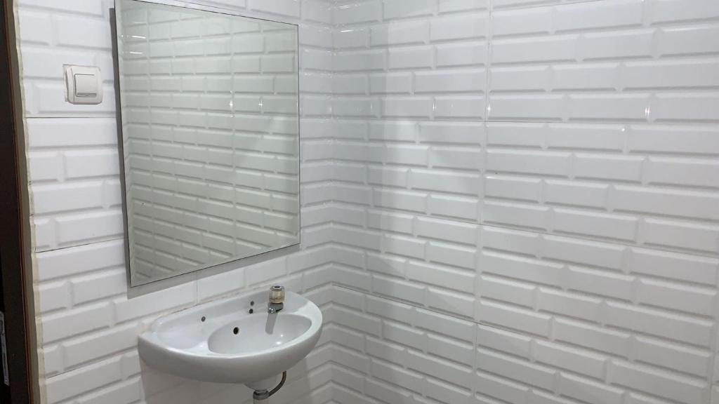 bagno bianco con lavandino e specchio di tekMIRA Hotel a Bandung