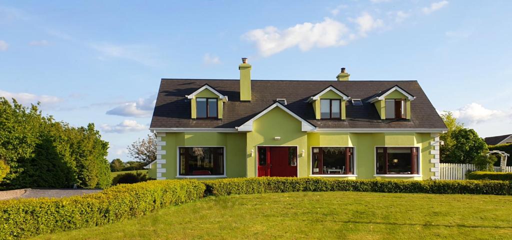 una casa verde con una puerta roja en un patio en Leroy´s Lodge en Headford