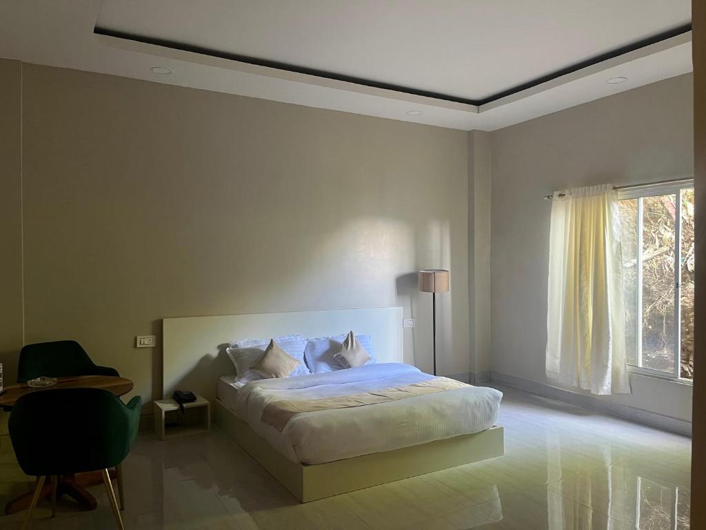 a white bedroom with a bed and a window at HOTEL RANSAM in Āīzawl