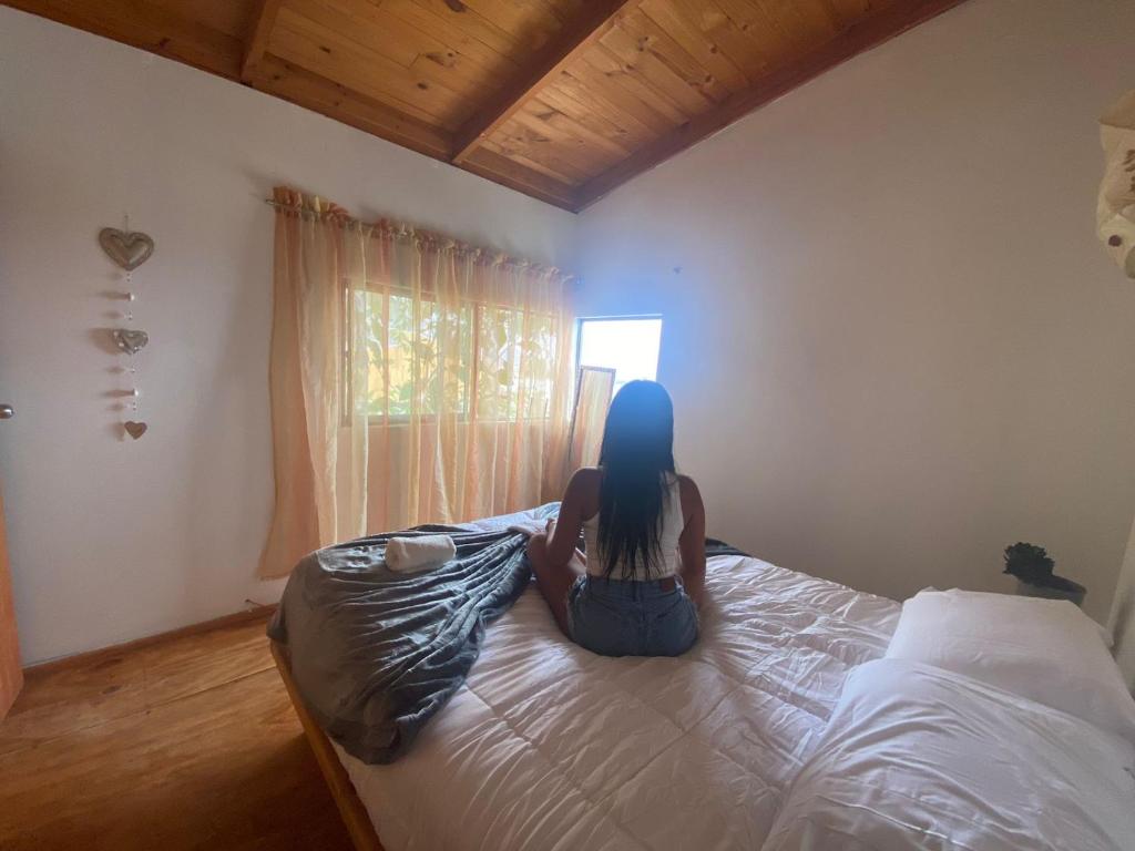 uma mulher sentada numa cama num quarto em Habitación Matrimonial en Totoralillo Glamping em Totoralillo
