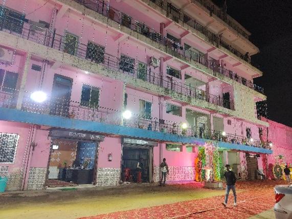 a pink building with people standing in front of it at Hotel Shobha in Rāmgarh