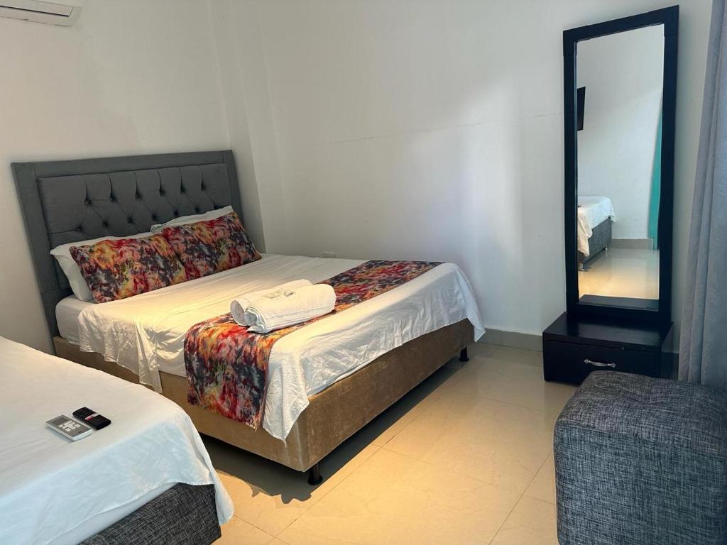 a bedroom with two beds and a mirror at Hotel CastilloMar in Cartagena de Indias