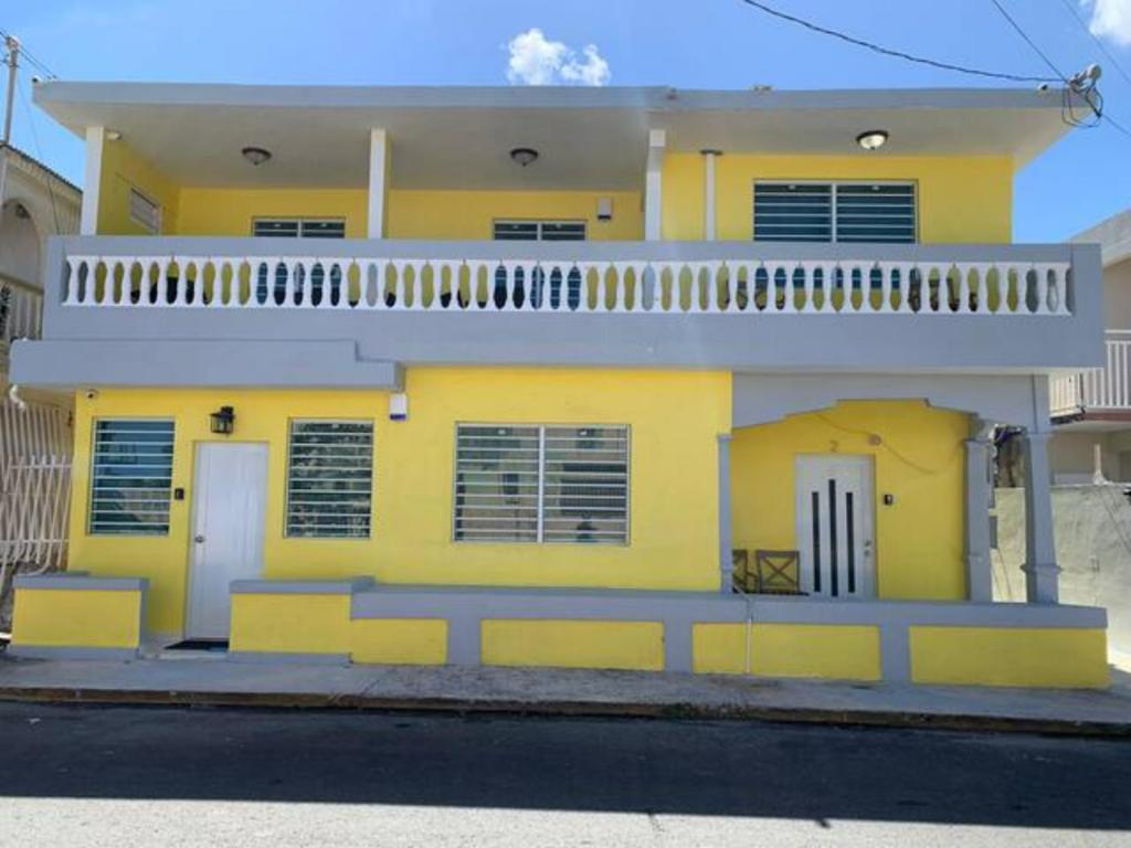 a yellow house with a balcony on top of it at Chic 3 Bedroom Unit, Few Steps To The Ocean, Barbosa Unit 4 in Catano