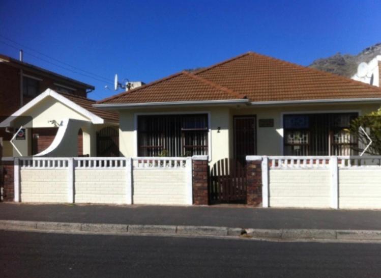 a white fence in front of a house at Prestone Cottage in Cape Town
