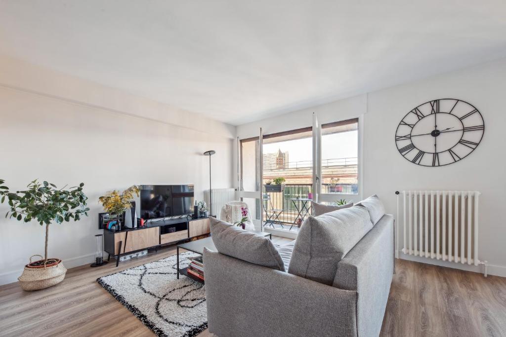 un salon avec un canapé et une horloge au mur dans l'établissement Symphonie de l'élégance à javel by Weekome, à Paris