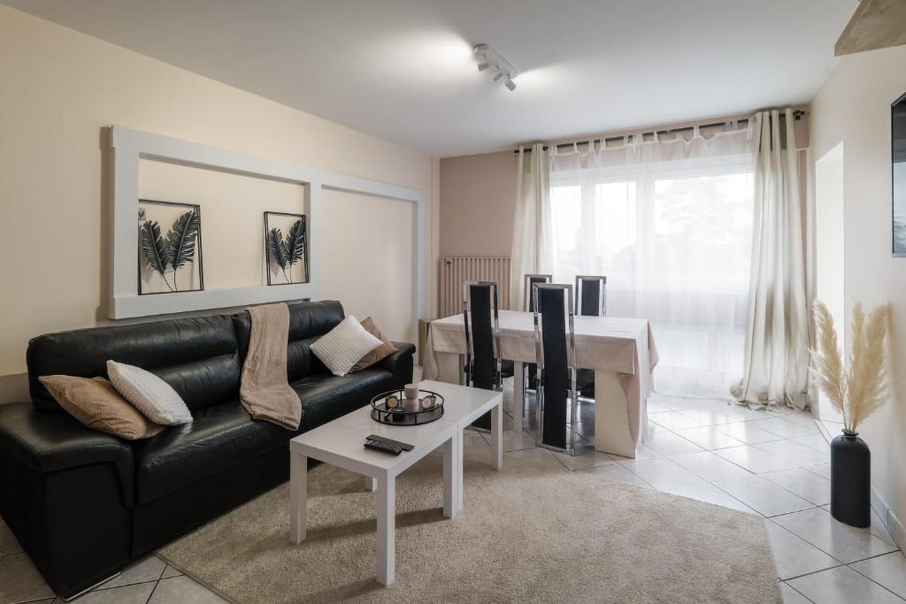 a living room with a black leather couch and a table at APPARTEMENT ARENA/ GROUPAMA STADIUM/ EUREXPO in Décines-Charpieu