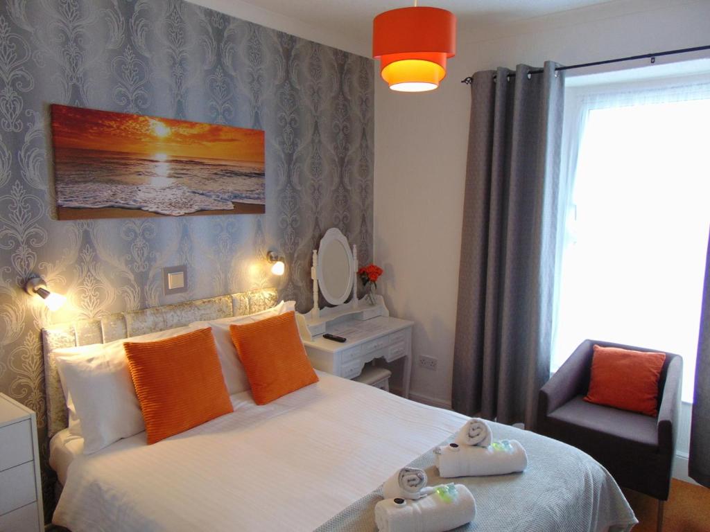 a bedroom with a bed with orange pillows and a chair at Seacroft Guest House in Paignton