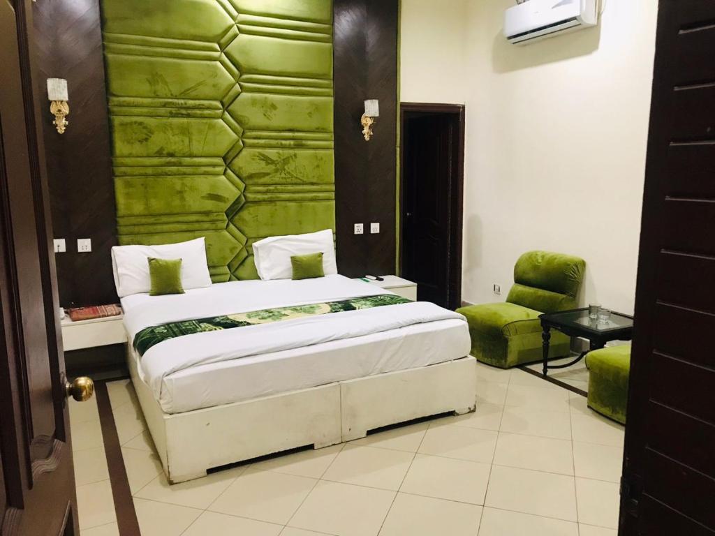 um quarto com uma cama e uma parede verde em Hotel PAK Continental Multan em Multan