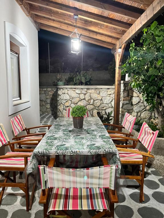 stół i krzesła na patio z kamienną ścianą w obiekcie Villa-Skalia / Kalymnos House w mieście Kalimnos