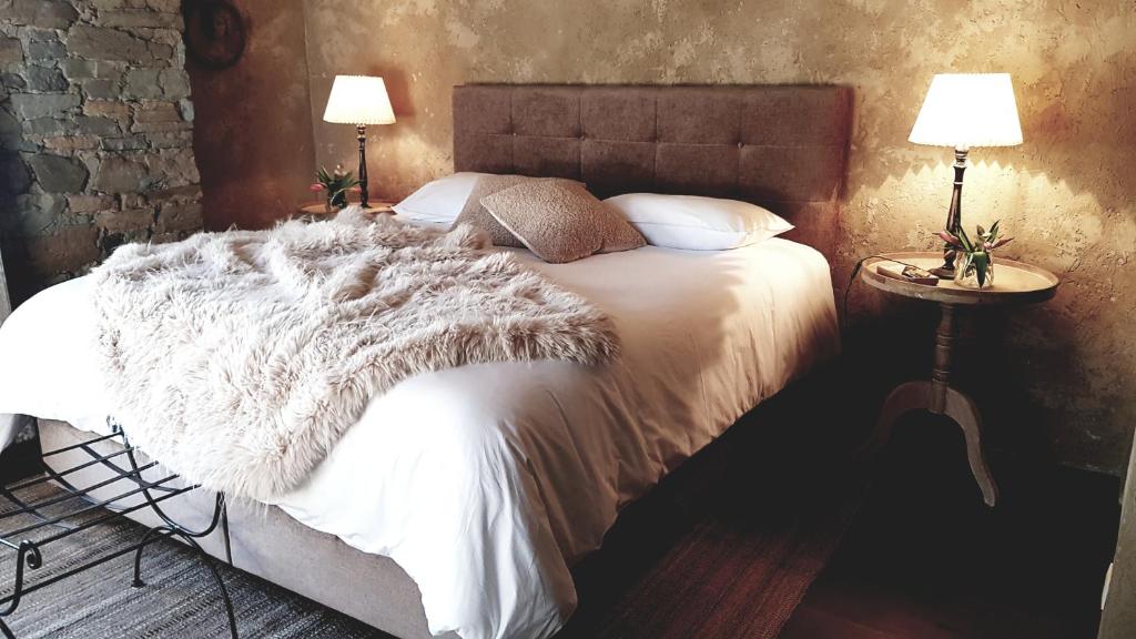 a bedroom with a bed with a white blanket and two lamps at Le Lodge des Flâneurs in Vielsalm