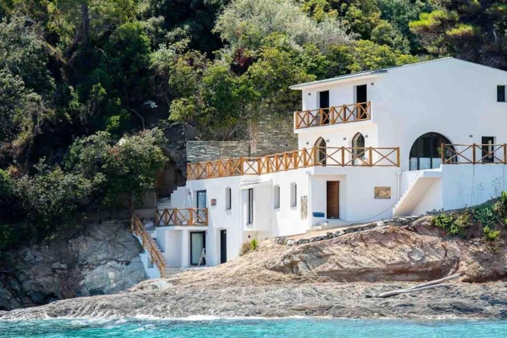 a white house on a hill next to the water at Villa prestige au bord de l'eau- Misincu in Cagnano