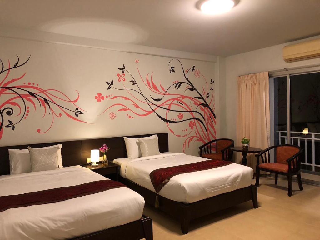 a bedroom with two beds and a painting of birds at NAKA GUEST HOUSE in Ban Ko Kwang