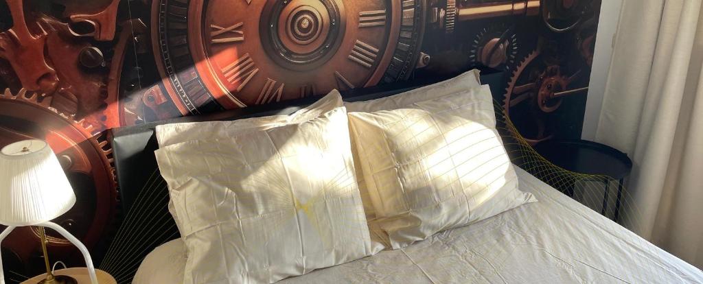 a bed with two pillows and a clock behind it at BnB Goldies in Eindhoven