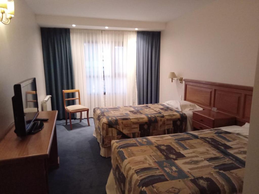 um quarto de hotel com duas camas e uma televisão em HOTEL SANTA CRUZ em Río Gallegos