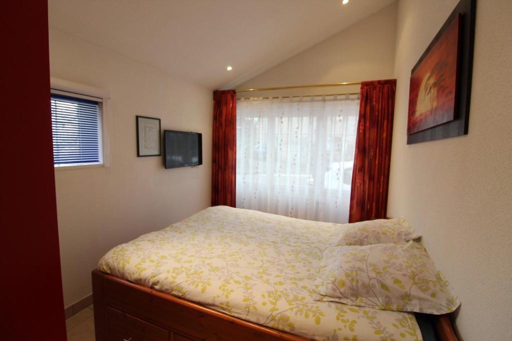 małą sypialnię z łóżkiem z oknem w obiekcie Le Parigney 