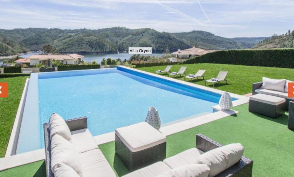 une grande piscine avec des chaises et un canapé dans l'établissement Apartamentos do Lago, à Ferreira do Zêzere