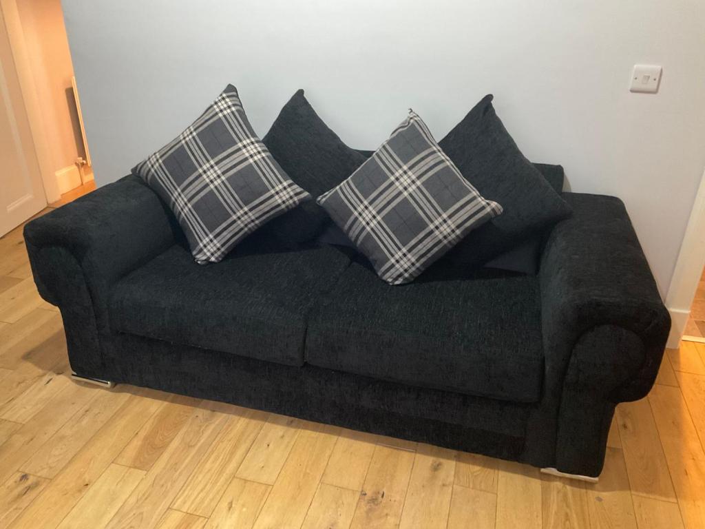 Un sofá negro con cuatro almohadas. en 105 Nelson str Ground Right en Largs