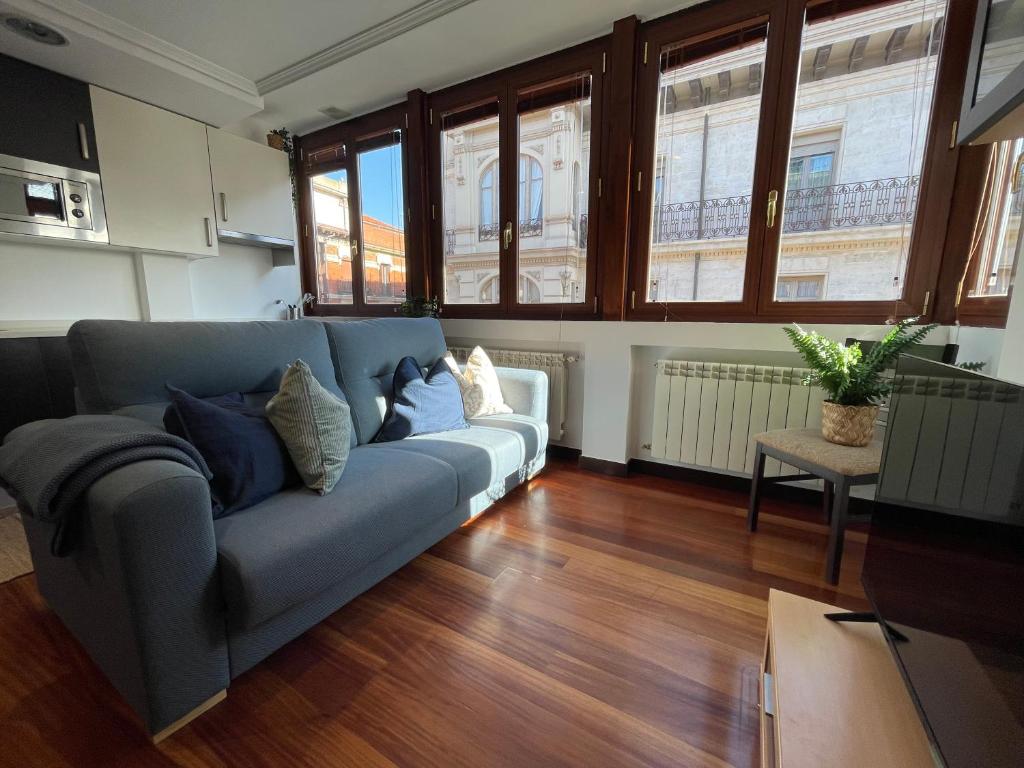 een woonkamer met een blauwe bank en een aantal ramen bij Atuaire Home Luz de Burgos II Centro con Parking Incluido in Burgos