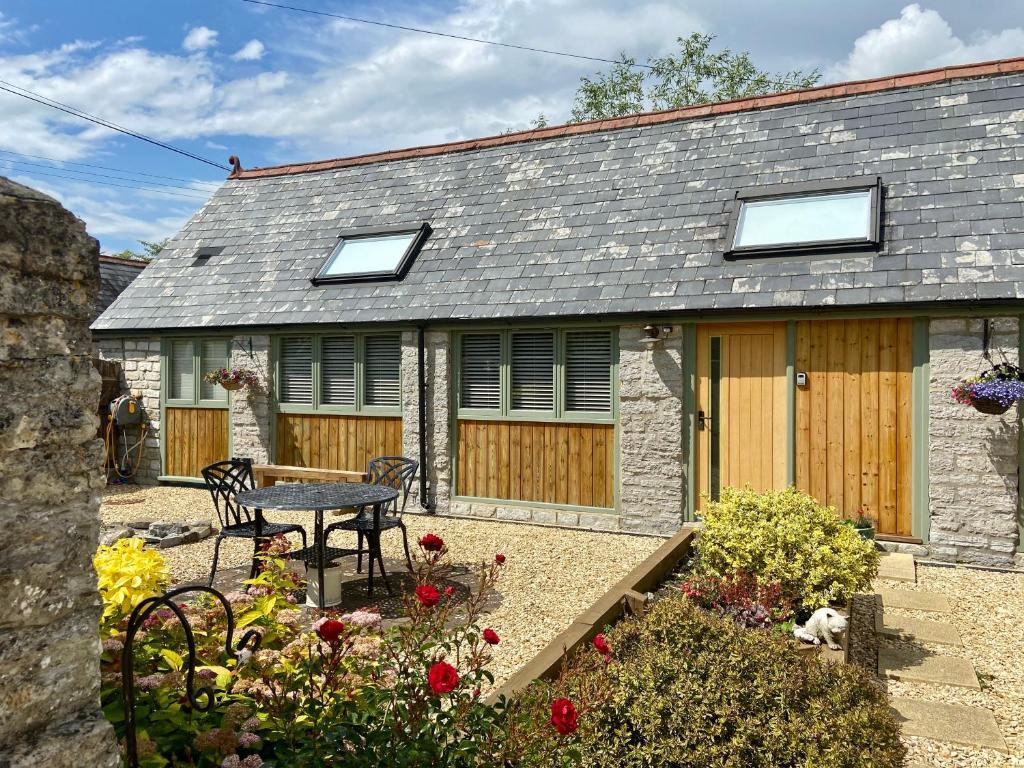 a stone cottage with a table and chairs in a garden at Church Farm Barn Annex in Somerton