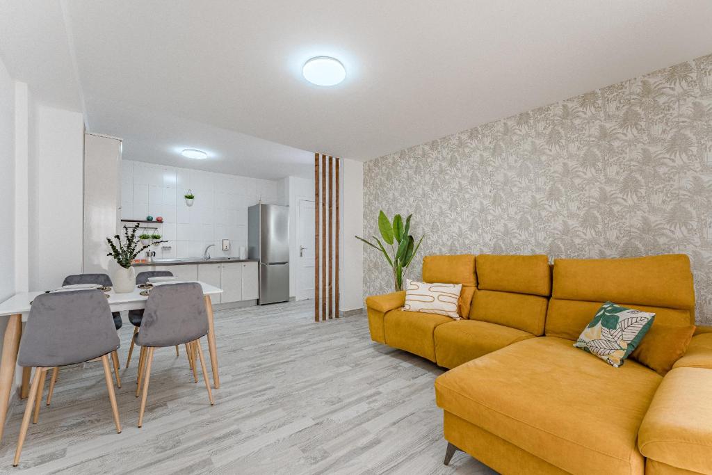 a living room with a yellow couch and a kitchen at TULUM MEDANO BEACH in El Médano