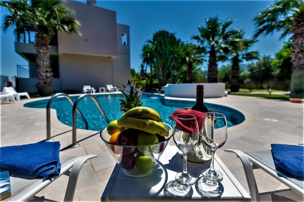 蒂加基的住宿－XENOS VILLA 2 near the sea，一张桌子,上面放着一碗水果和一瓶葡萄酒